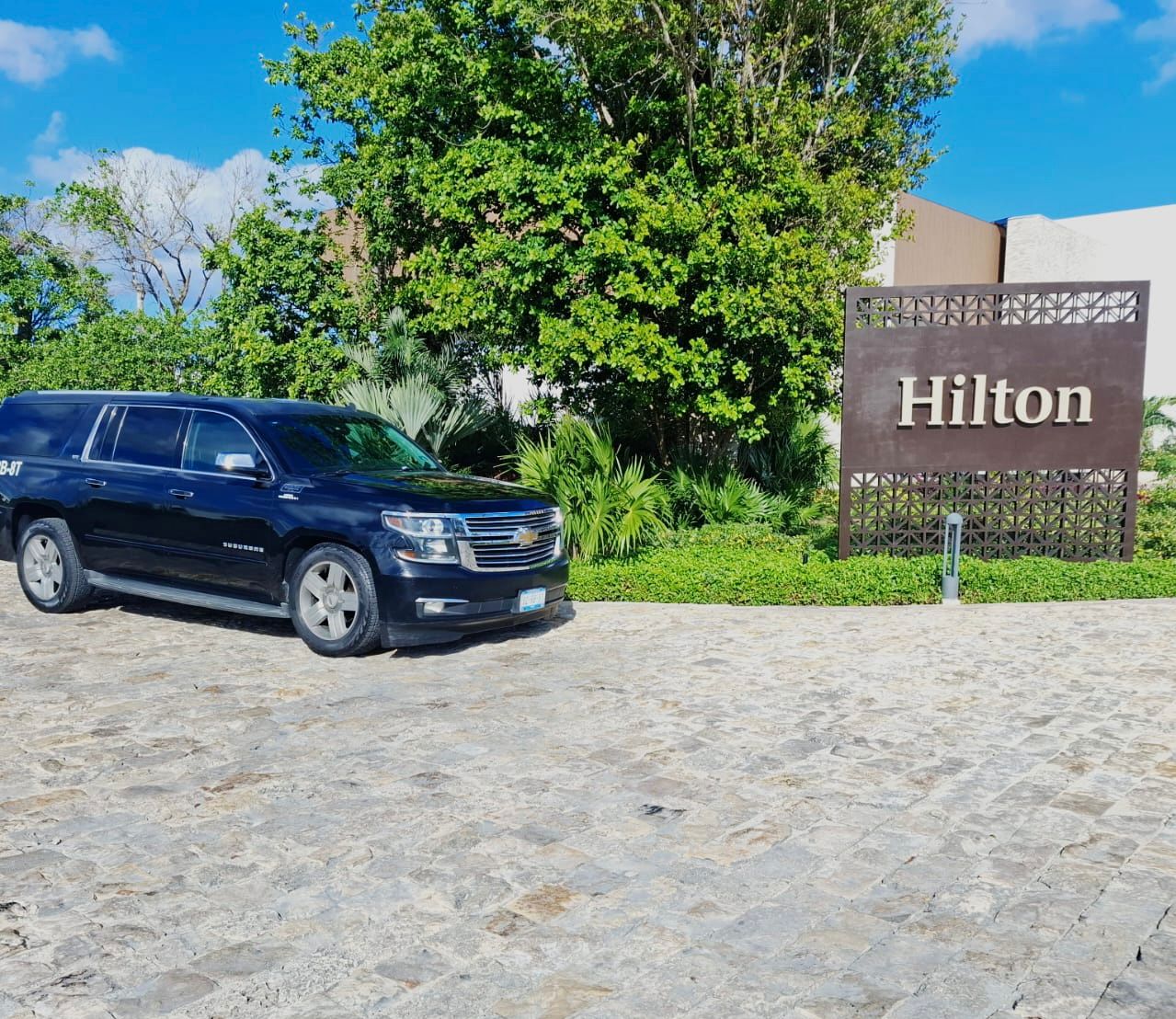 Black Chevrolet Suburban positioned outside a Hilton property in Cancun for hotel pickup service.