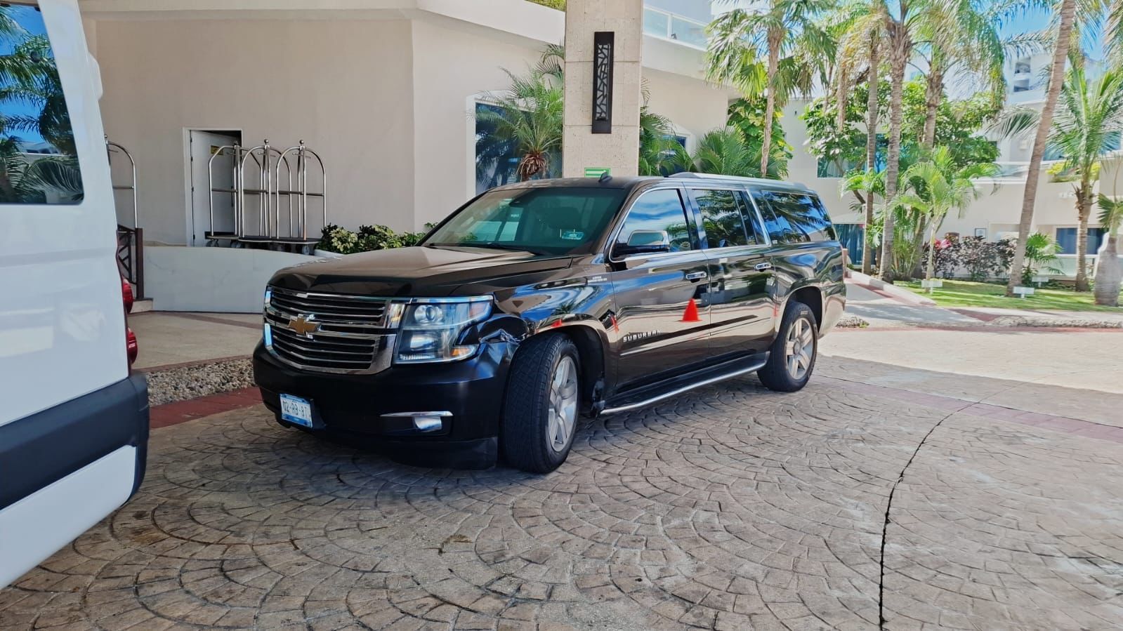 Black Chevrolet Suburban waiting at a hotel entrance in Cancun for private passenger pickup.