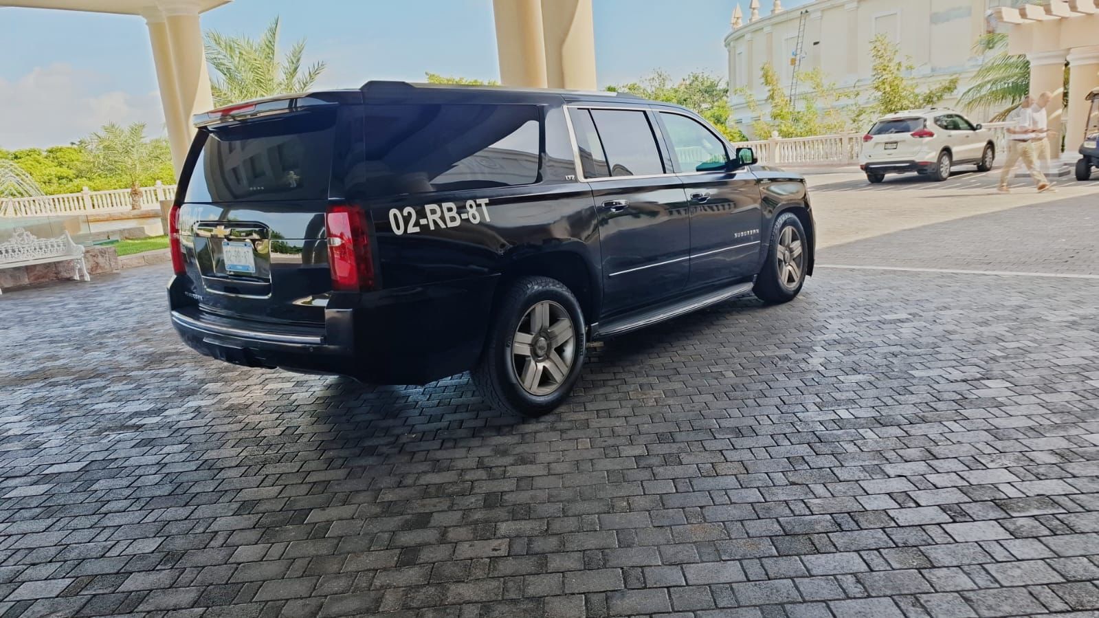 Black Chevrolet Suburban under a luxury resort portico for executive ground transportation.