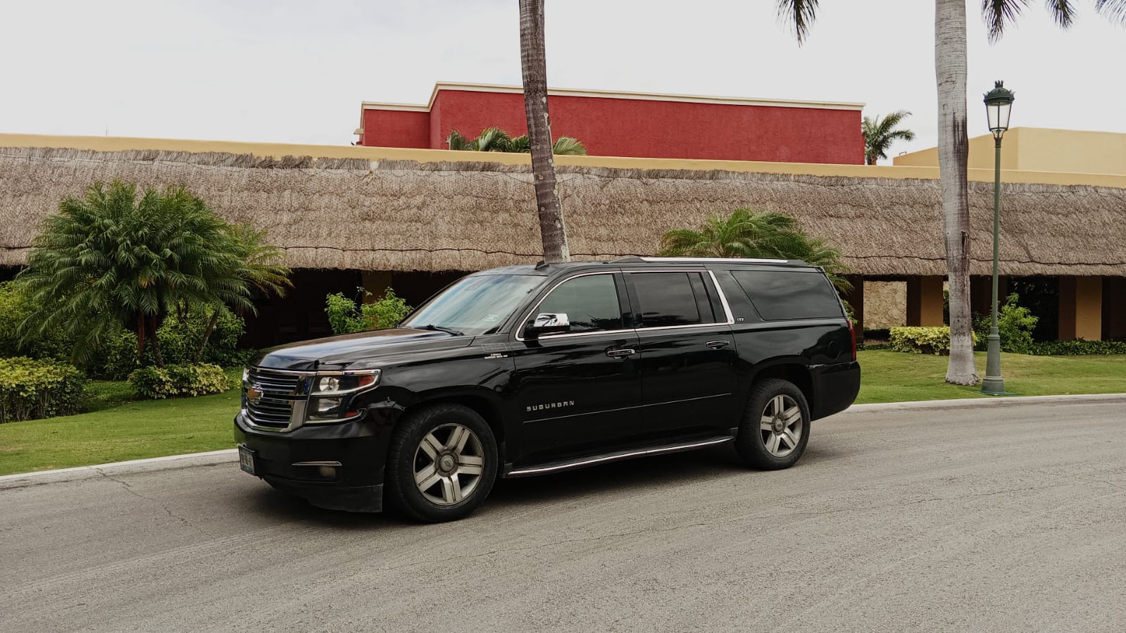 Black Chevrolet Suburban parked on a resort driveway in Cancun ready for private passenger pickup.