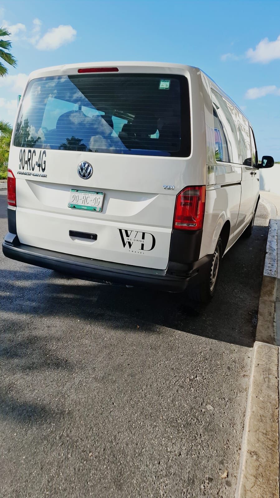 White transfer van from We Drive Travel parked roadside in Riviera Maya for passenger transportation.